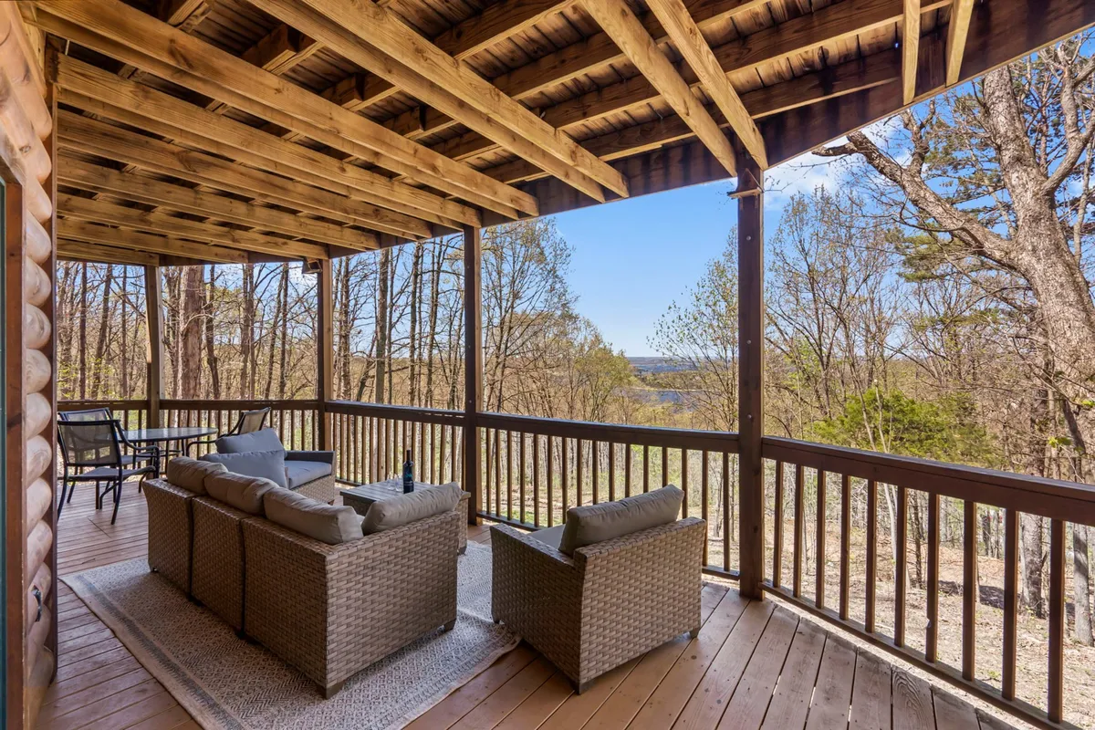 This image showcases a spacious outdoor seating area on a wooden deck, featuring rustic railings, comfortable chairs, and a scenic view of the surrounding landscape. The open-air environment is perfect for group gatherings, relaxing with friends, or taking in the sunset together.