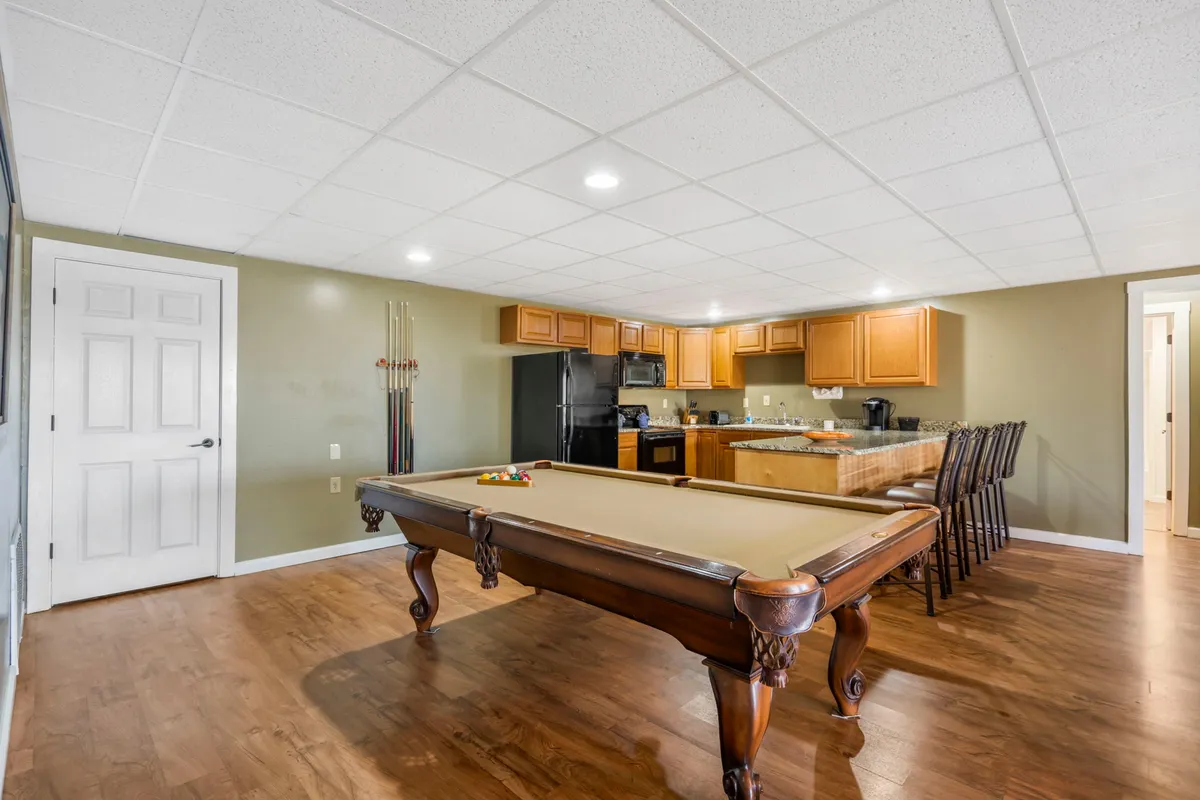 A relaxed, social recreation room with a pool table, kitchen area, and bar stools. The scene hints at easy access to snacks and drinks during games or gatherings, supporting extended family time and seamless entertaining.