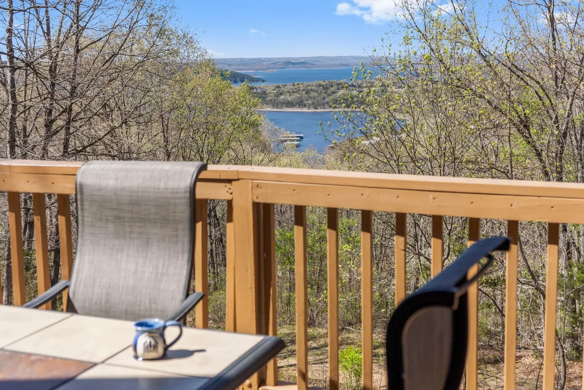 A peaceful lake view from the lodge's deck, complete with wooden railings and comfortable outdoor furniture. The tranquil water and open sky set the scene for memorable moments, such as sunrise coffees, sunset drinks, or group barbecues after a day of Branson adventures.