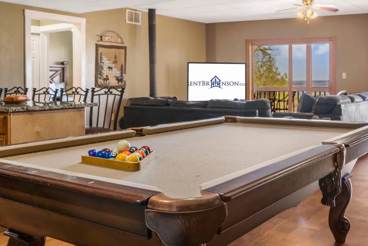 A bright, inviting recreation area combining a pool table, a comfortable sofa, a television, and a window with a view. The space is ideal for both playing games and relaxing, supporting movie marathons or friendly rivalry, all in a cozy yet open setting.