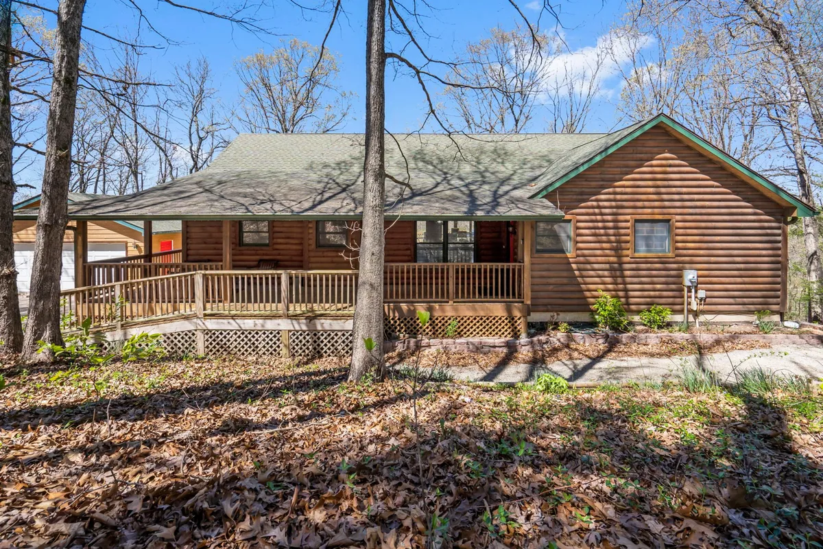 A charming log cabin with a welcoming wooden porch nestled among natural surroundings. The porch faces the woods, providing a perfect spot to relax after outdoor exploration. The cabin's rustic appeal and open porch evoke a cozy, pet-friendly atmosphere.